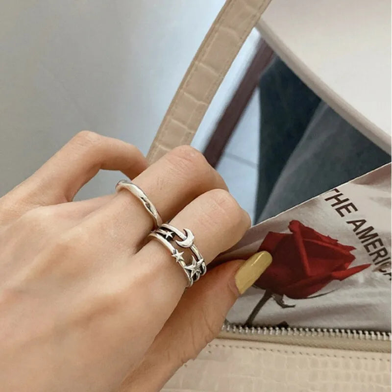 Hand wearing a silver ring with star and moon design, holding a magazine with a red rose cover.