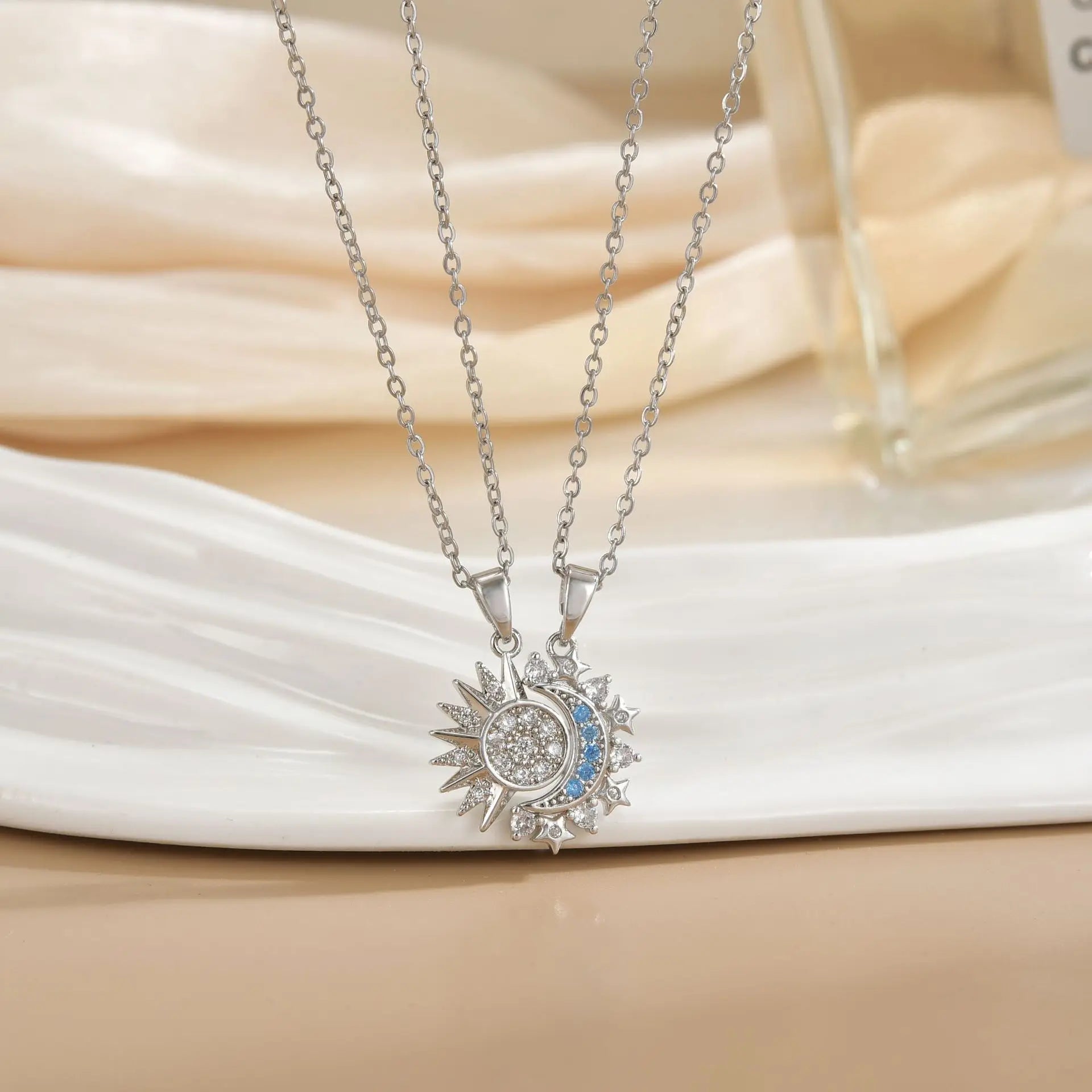 Silver necklace with a sun and moon pendant on a white surface