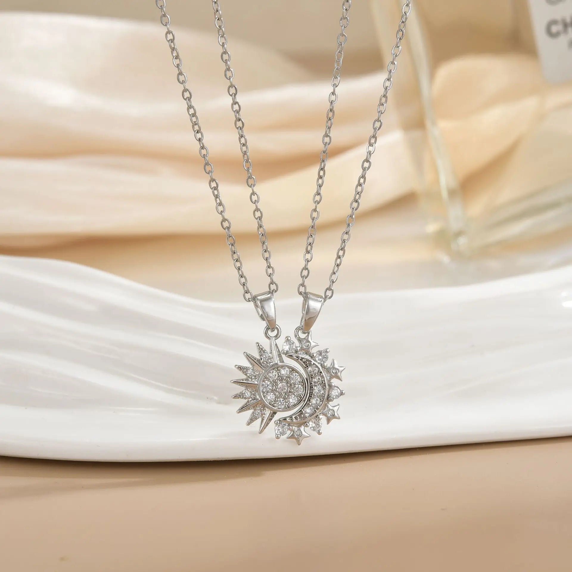 Silver necklace with sun and moon pendant on a white fabric background