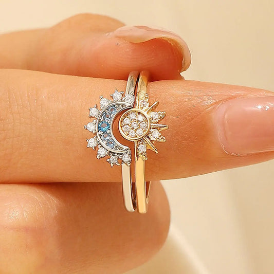 Gold ring with sun and moon design on a finger against a beige background