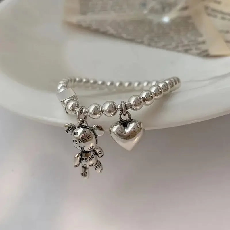 Silver beaded bracelet with charms on a white dish