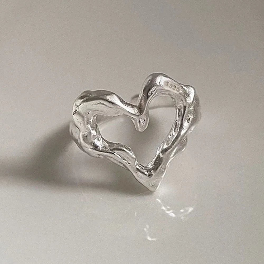 Silver heart-shaped ring on a light gray background