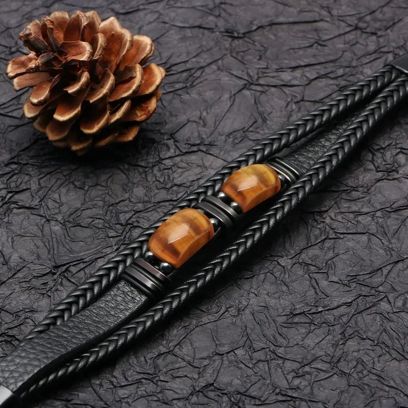 Black braided leather bracelet with brown beads on a textured black surface
