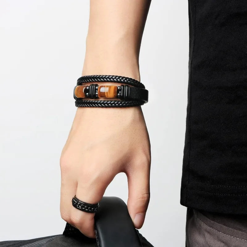 Hand wearing a black braided bracelet on a plain background