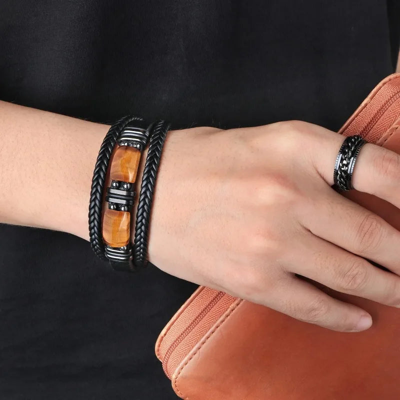 Close-up of a wrist wearing a black braided bracelet with an orange stone and a matching ring on a dark background.