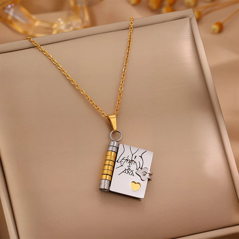 Gold and silver necklace with a book-shaped pendant on a beige surface