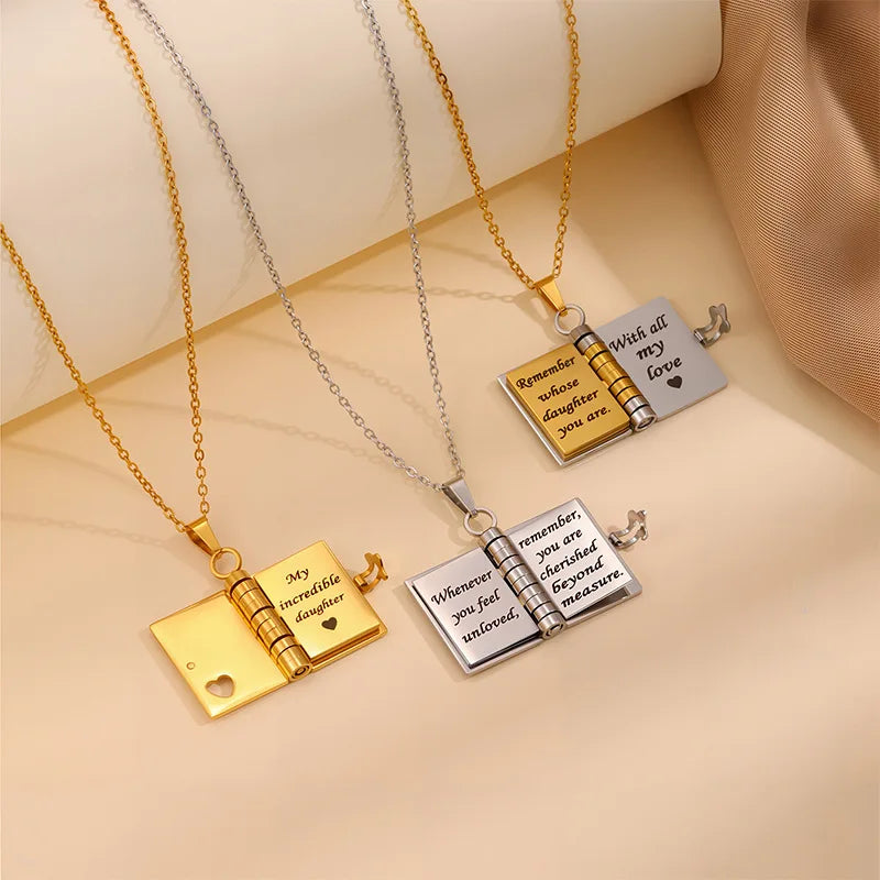 Three book-shaped pendant necklaces on a beige background