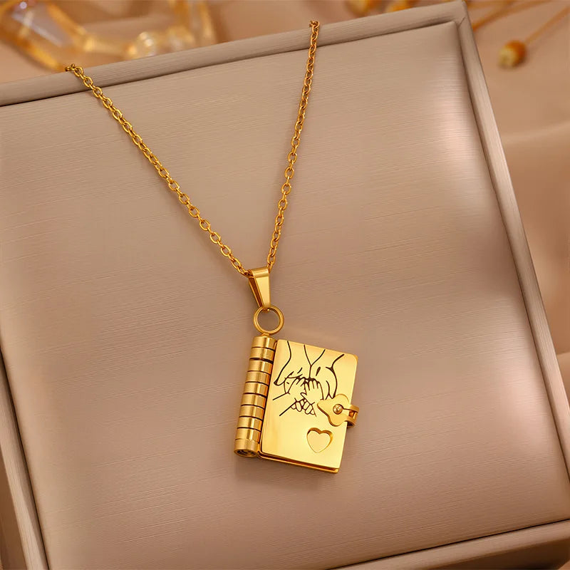 Gold necklace with a book-shaped pendant on a beige surface