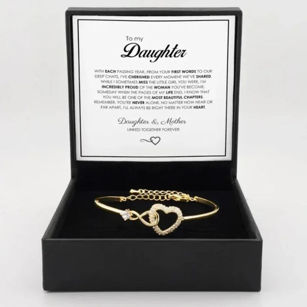 Gold bracelet with heart design in a black box with a message card, on a white background