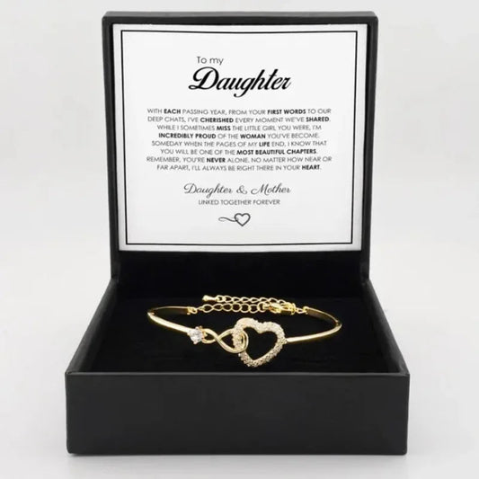 Gold bracelet with heart design in a black box with a message card, on a white background