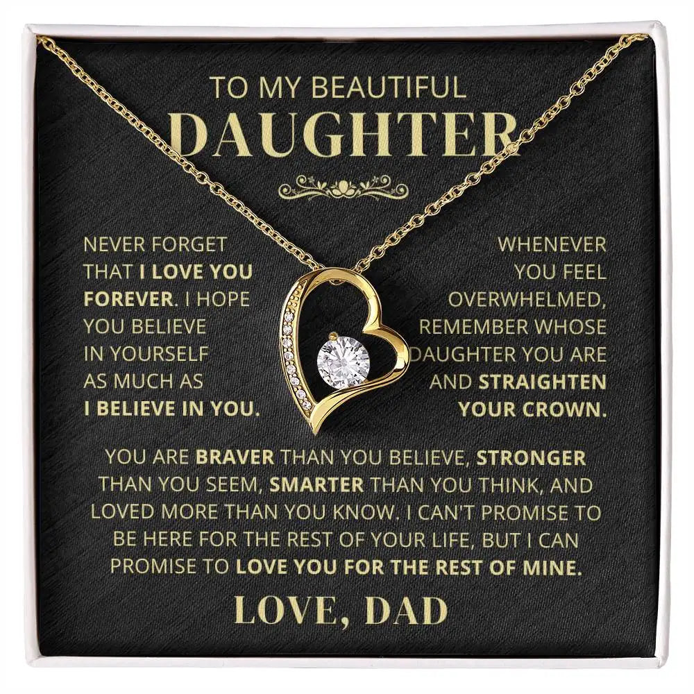 Gold necklace with heart design on a black card with gold text, featuring an inspirational message.