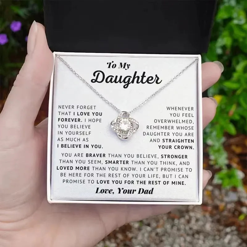 Necklace with a sentimental message card held by a hand outdoors.