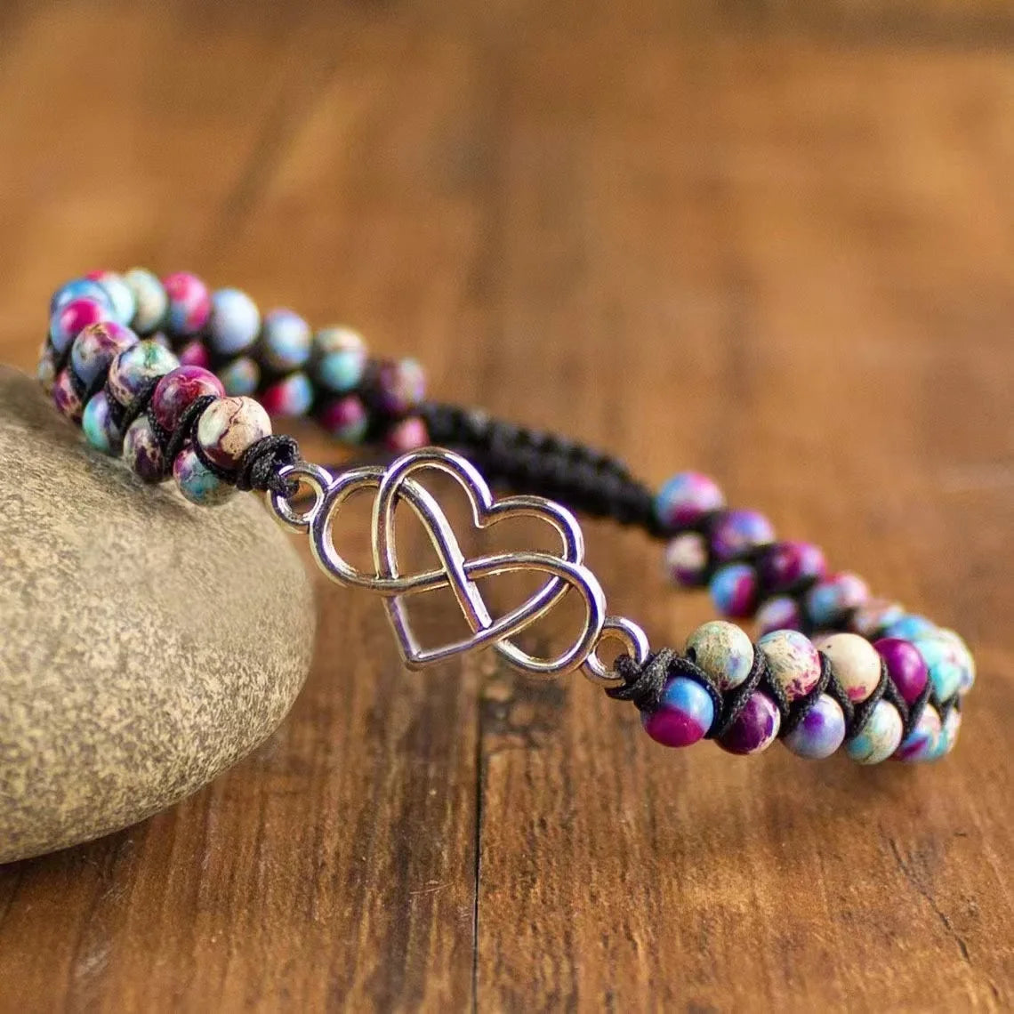 Beaded bracelet with a metal heart charm on a wooden surface
