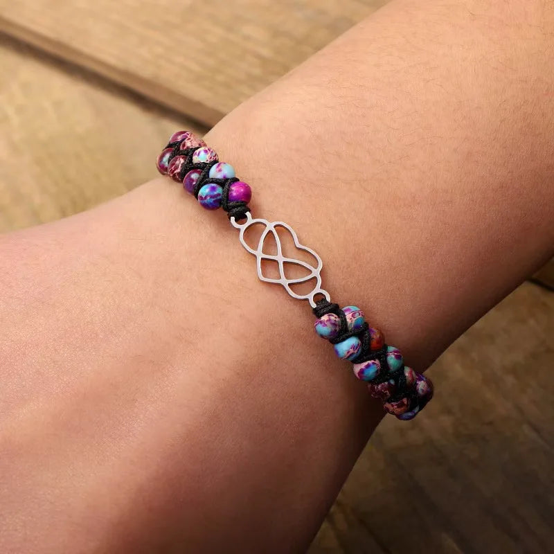 Multicolored beaded bracelet with a silver charm on a wrist against a wooden background