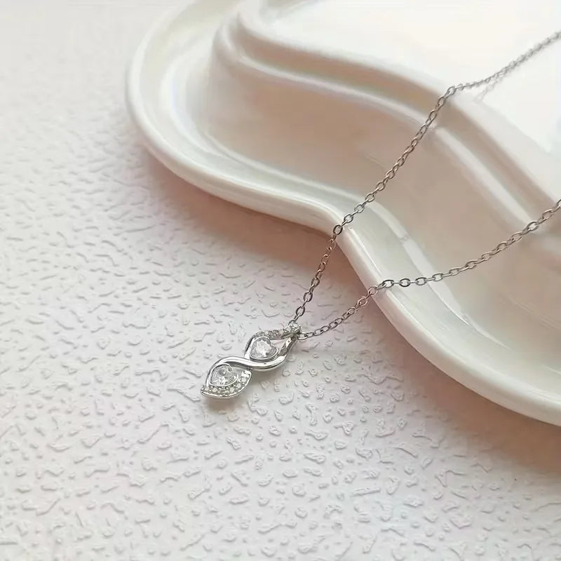 Silver necklace with a delicate pendant on a textured white surface