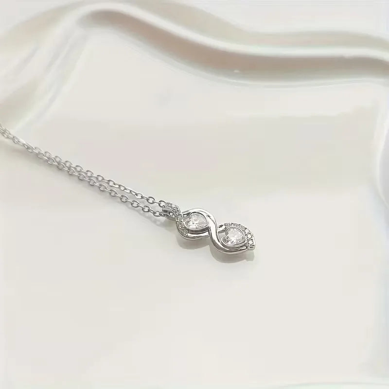 Silver necklace with a heart-shaped pendant on a white fabric background