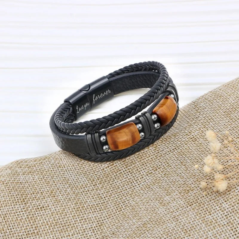Black braided bracelet with wooden accent on a textured surface