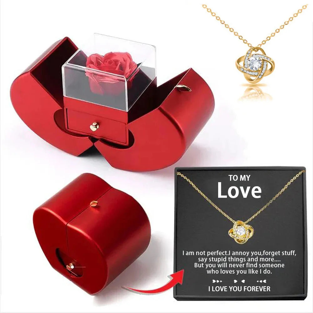 Red jewelry box with a rose, gold necklace with heart pendant, and sentimental card on a white background
