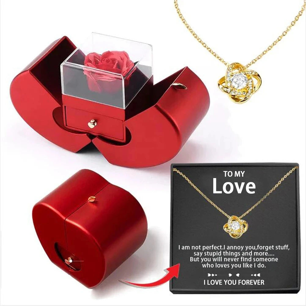 Red jewelry box with a rose, gold necklace with heart pendant, and sentimental card on a white background
