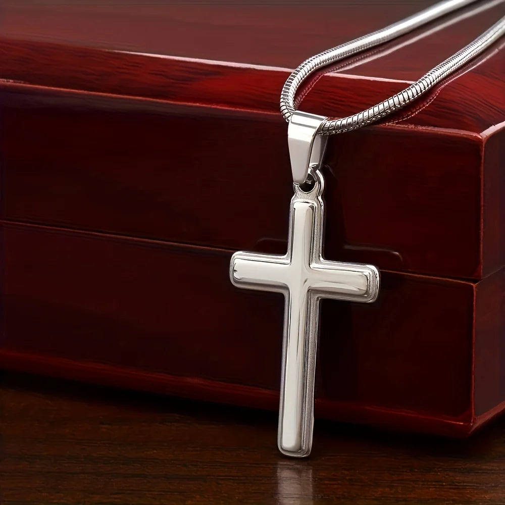 Silver cross pendant on a chain against a wooden background