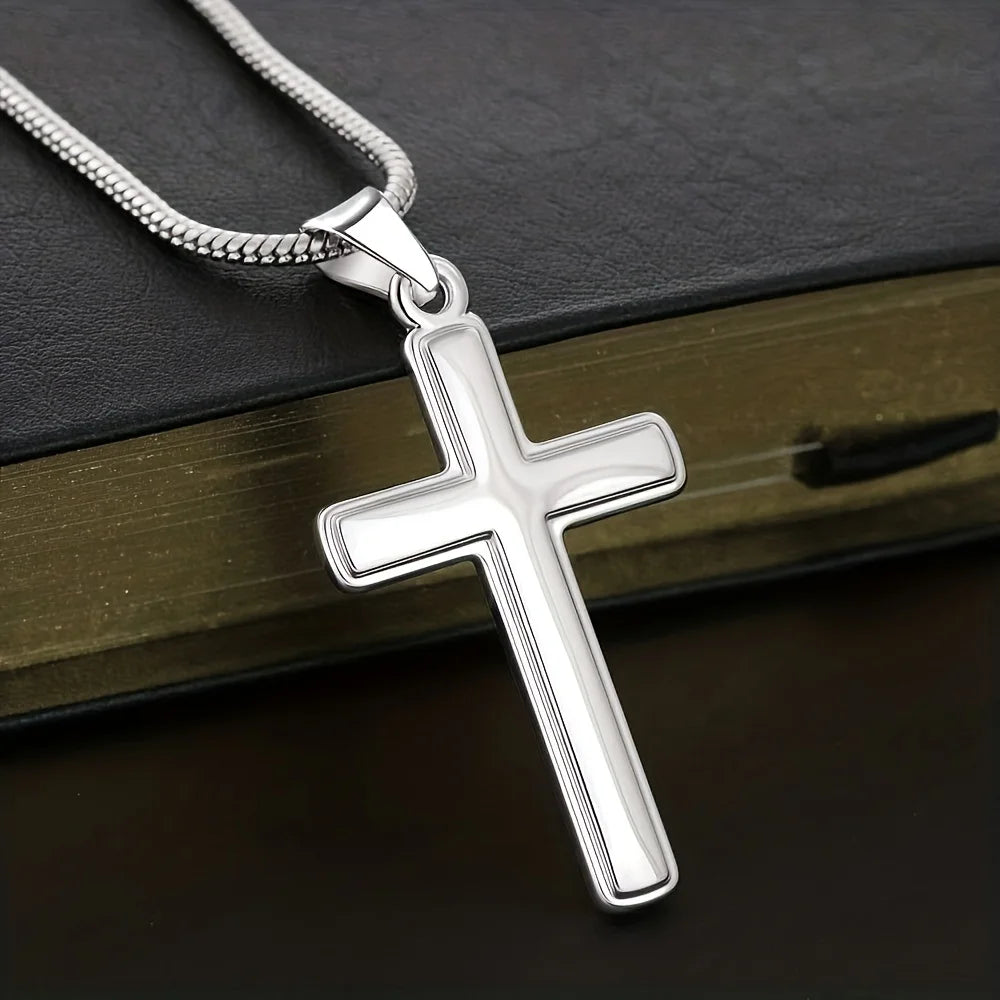 Silver cross pendant on a chain against a dark background