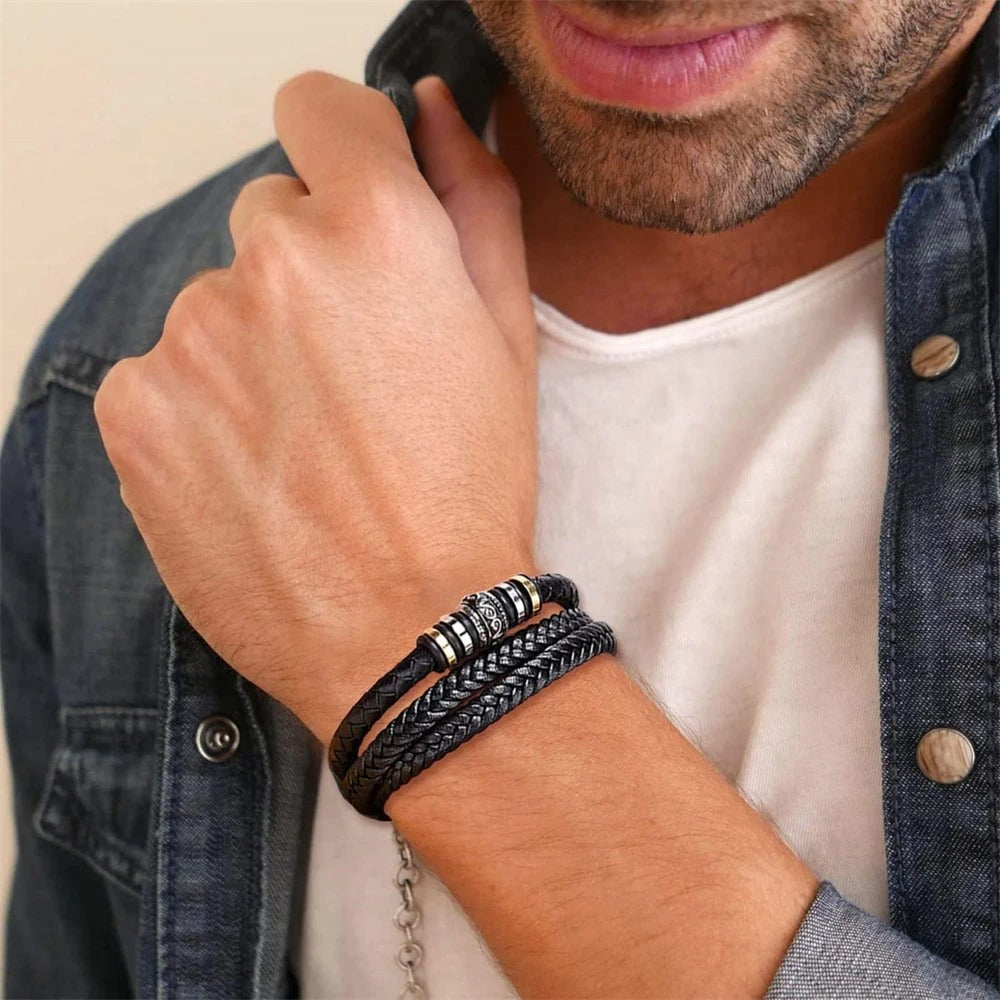 Man wearing multiple bracelets on his wrist with a neutral background