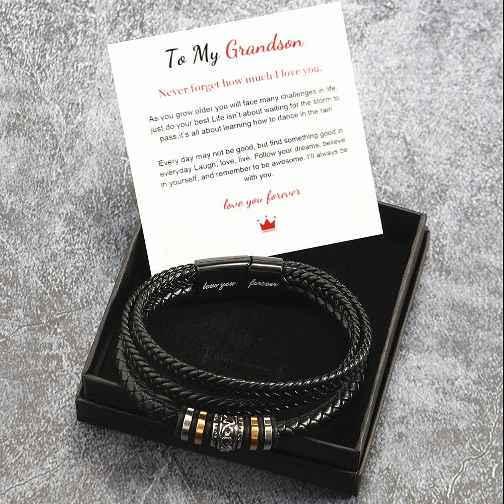 Black braided leather bracelet with gold accents on a card that reads 'To My Grandson' on a gray textured background.
