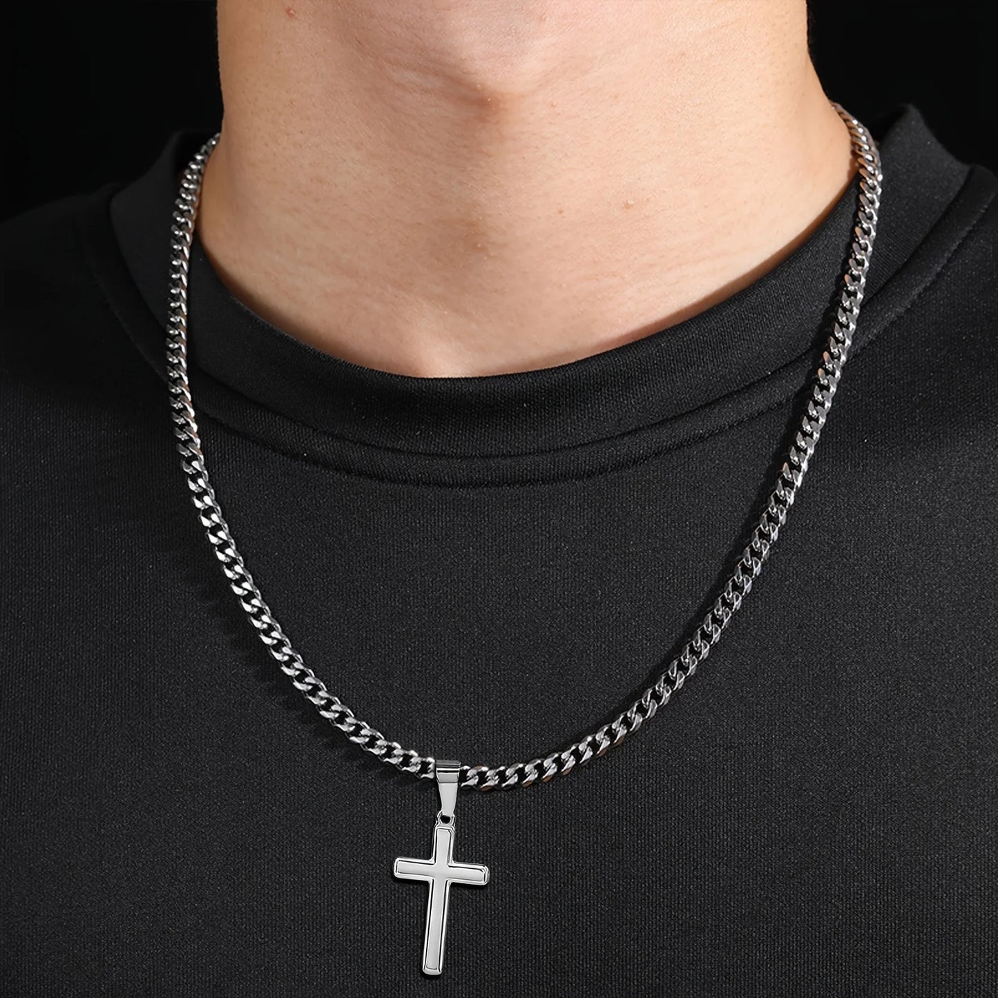 Silver chain necklace with a cross pendant on a black shirt