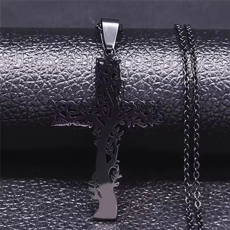 black tree-shaped cross pendant with chain on a textured black surface