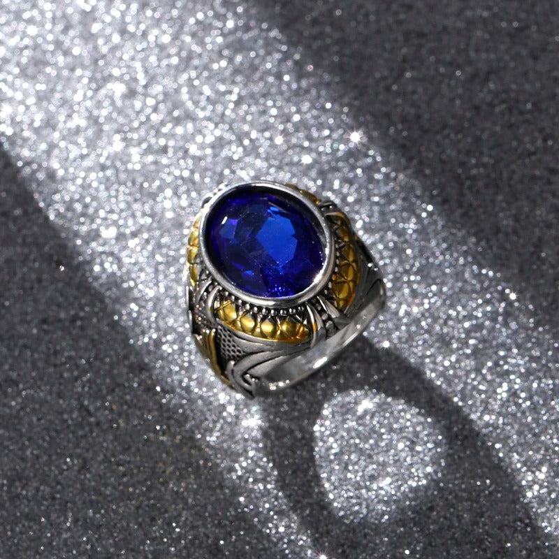 Ring with a blue gemstone and gold accents on a textured gray background
