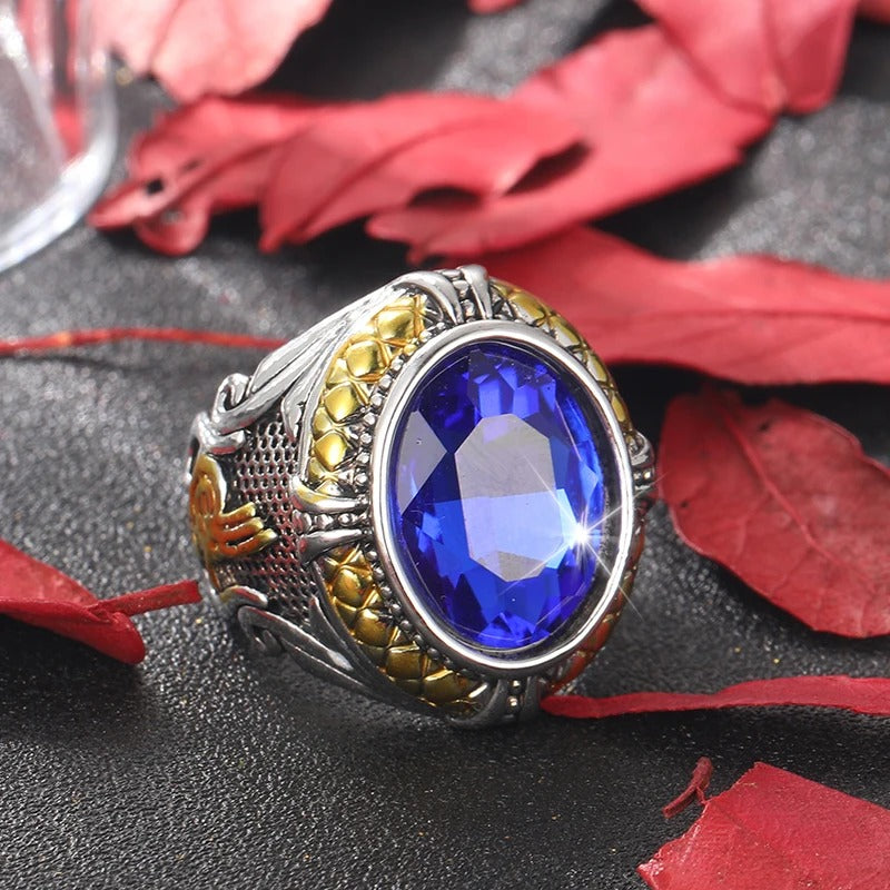 Ring with a blue gemstone on a dark surface with red leaves