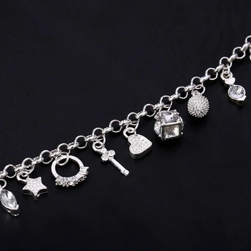 Silver charm bracelet with various charms on a black background