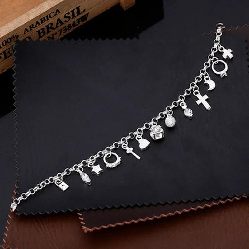 Silver bracelet with various charms on a dark surface