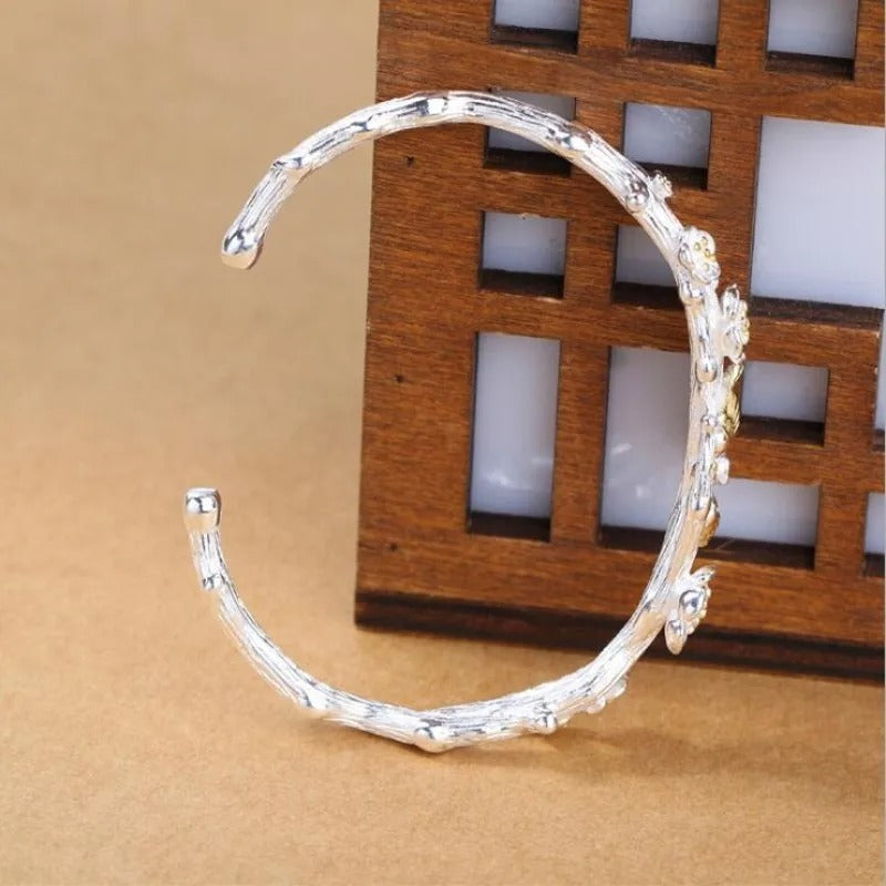 Silver bracelet with floral designs on a wooden background