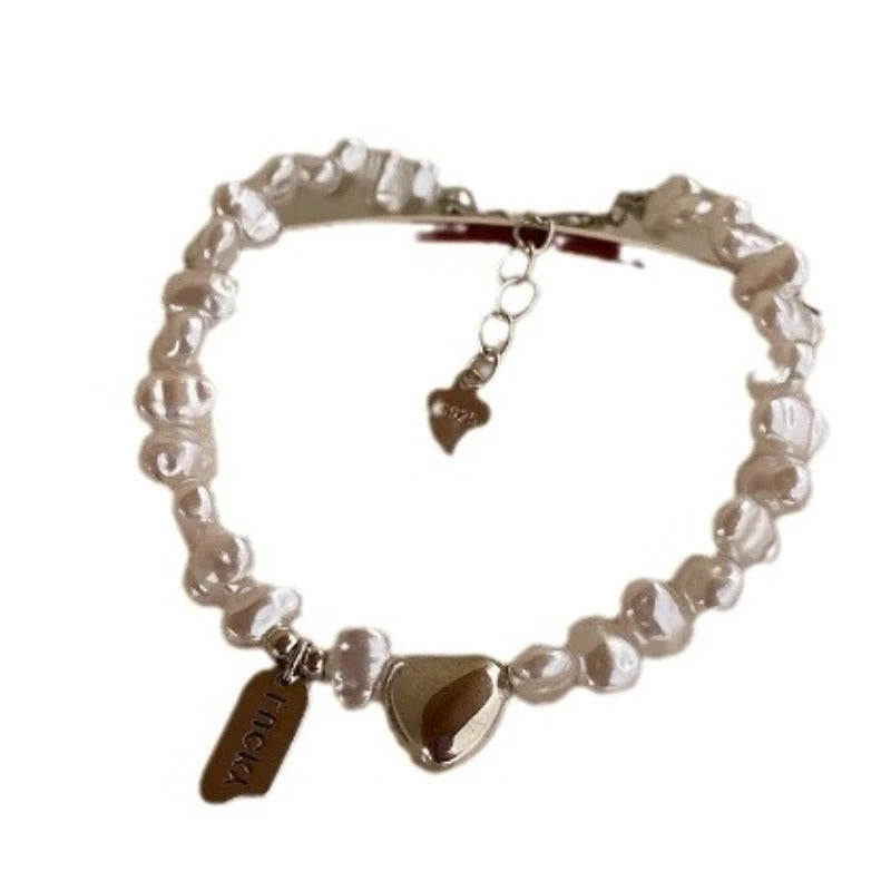 Pearl bracelet with heart-shaped charms on a white background