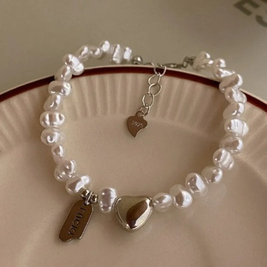 Pearl bracelet with heart-shaped charms on a ceramic plate