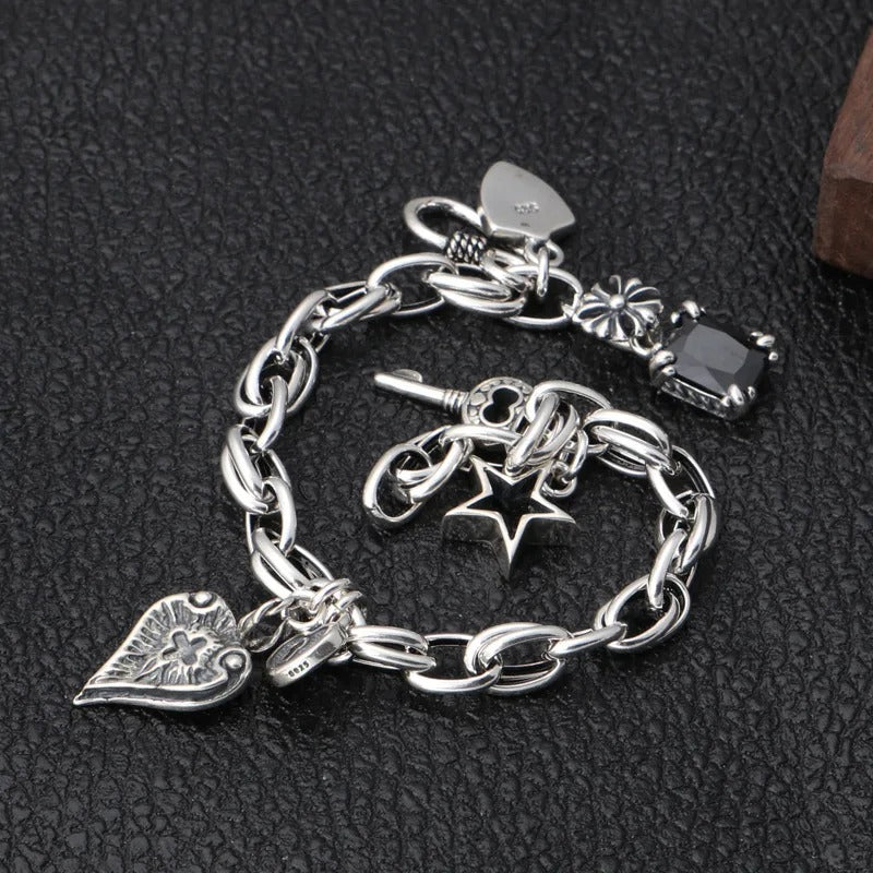 Silver charm bracelet with various charms on a dark textured background