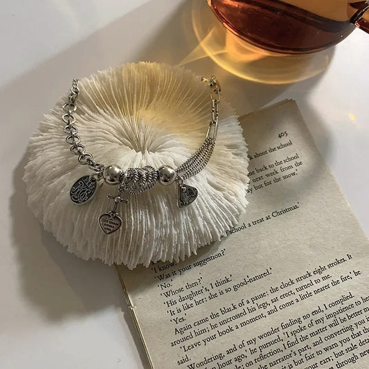 Bracelet with charms on a textured white surface next to an open book