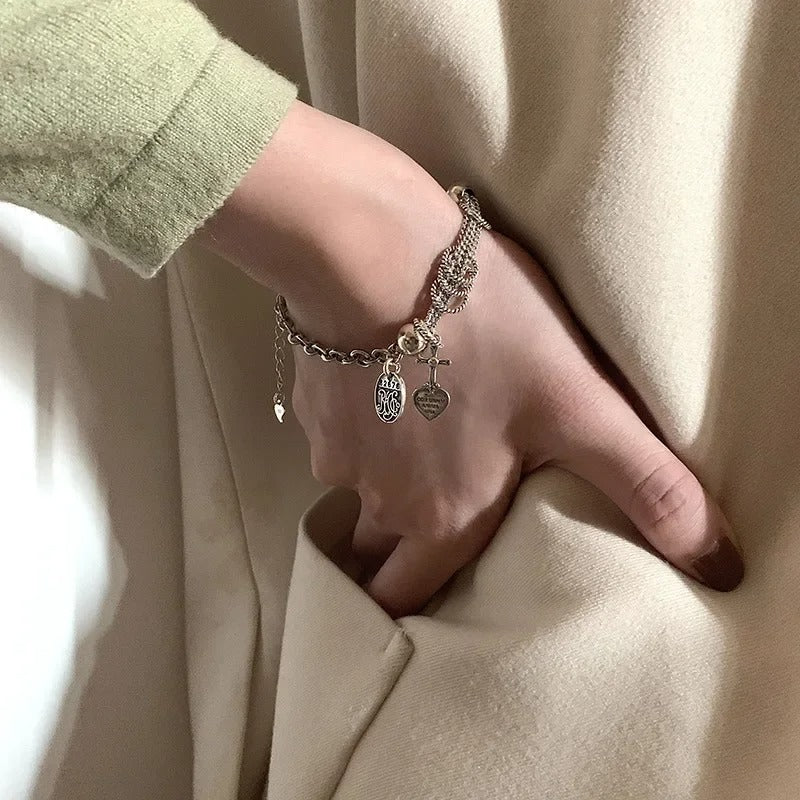Hand wearing a bracelet with charms against a beige background