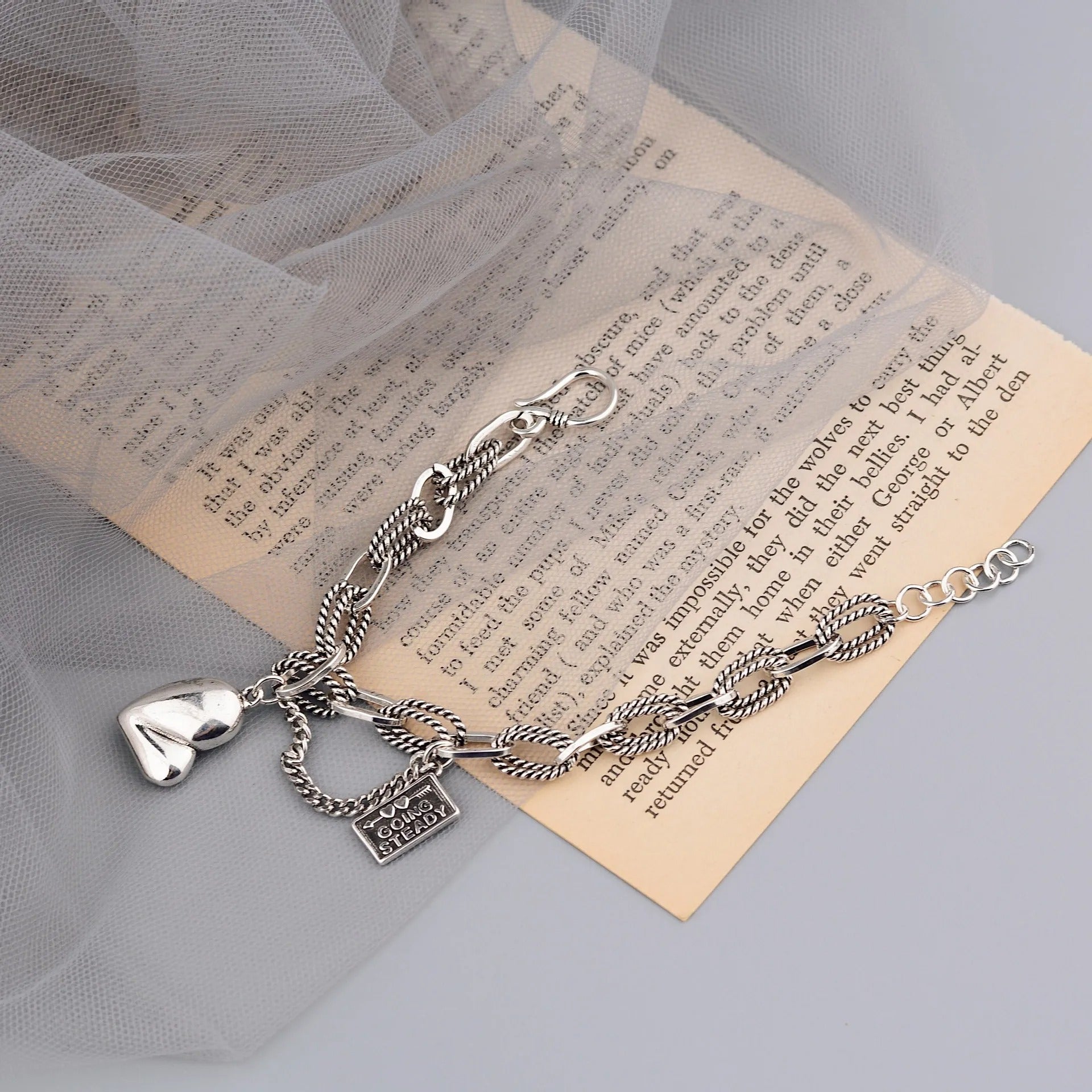 Silver bracelet with heart and lock charms on a piece of paper