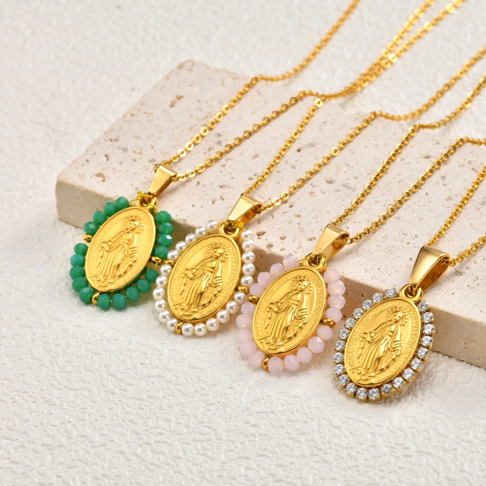 Gold necklaces with various pendants on a textured surface