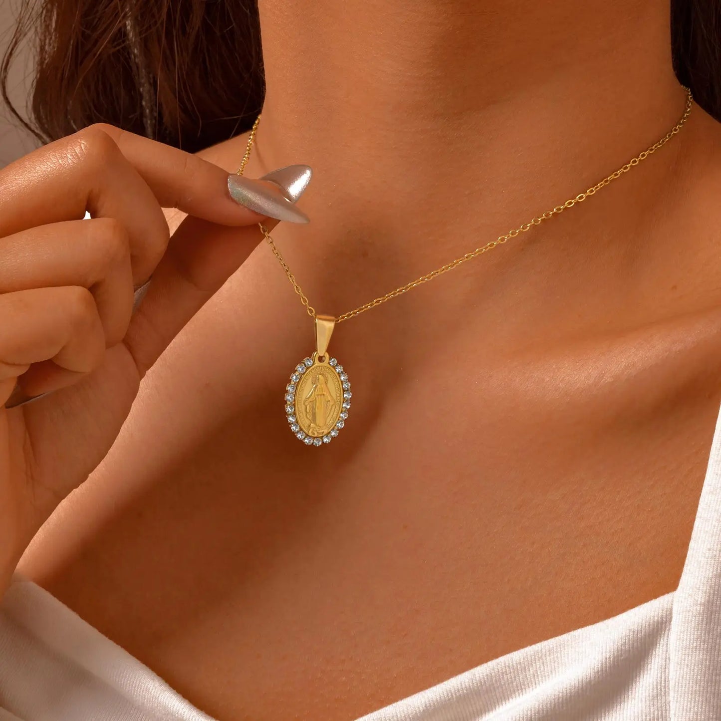Gold necklace with a pendant being worn on a person's neck.