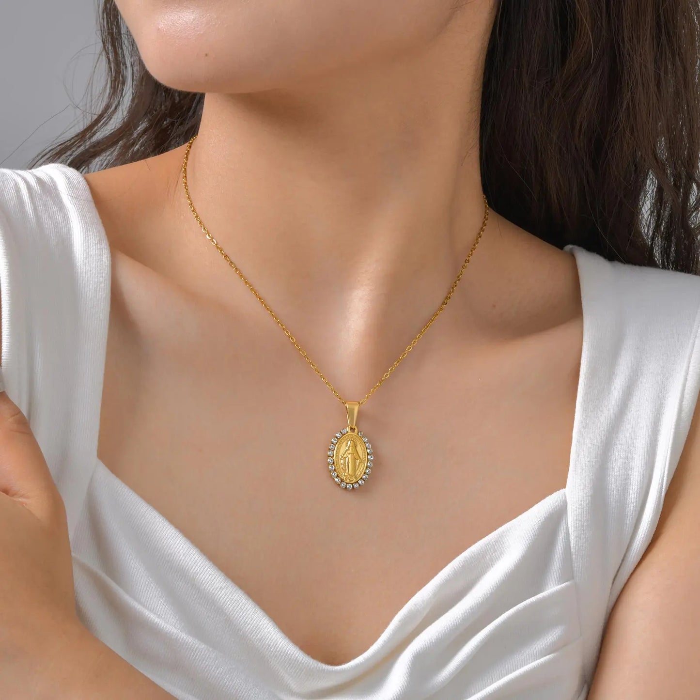 Gold necklace with a pendant worn by a person in a white top