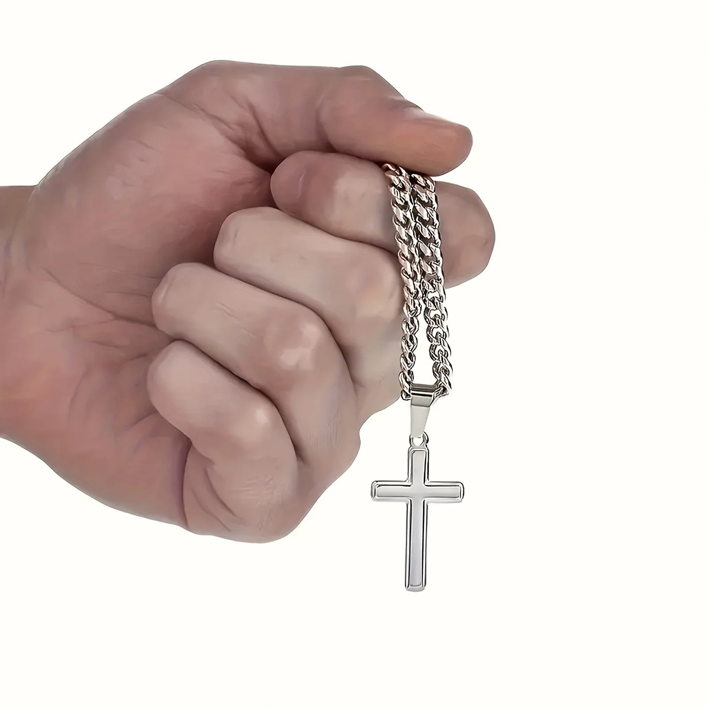 Hand holding a silver chain with a cross pendant on a white background