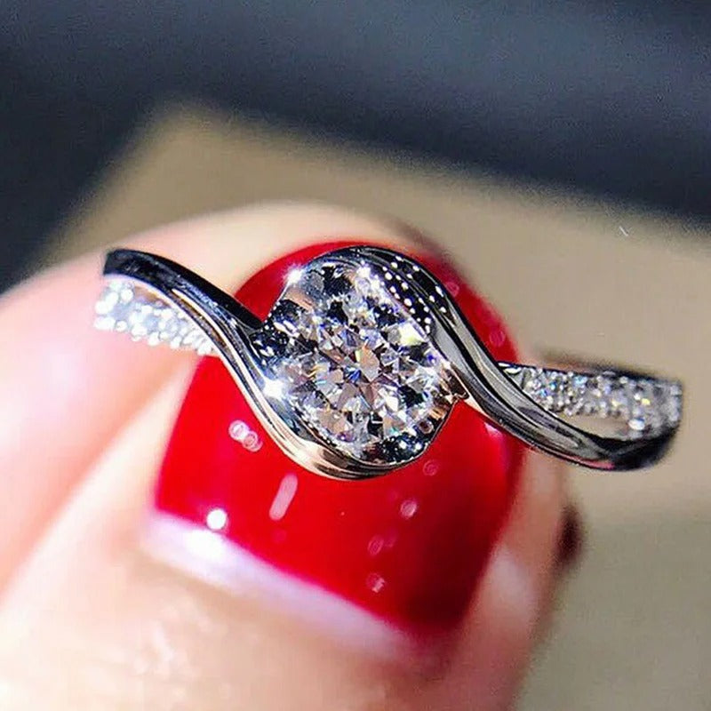 Silver ring with a diamond on a finger with red nail polish