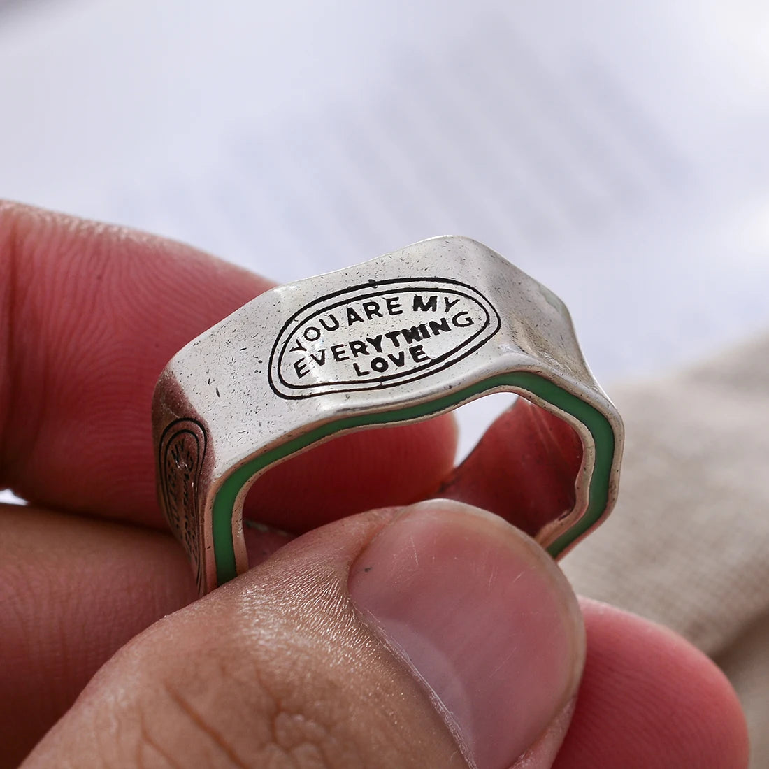 Ring with 'You Are My Everything Love' engraving held between fingers
