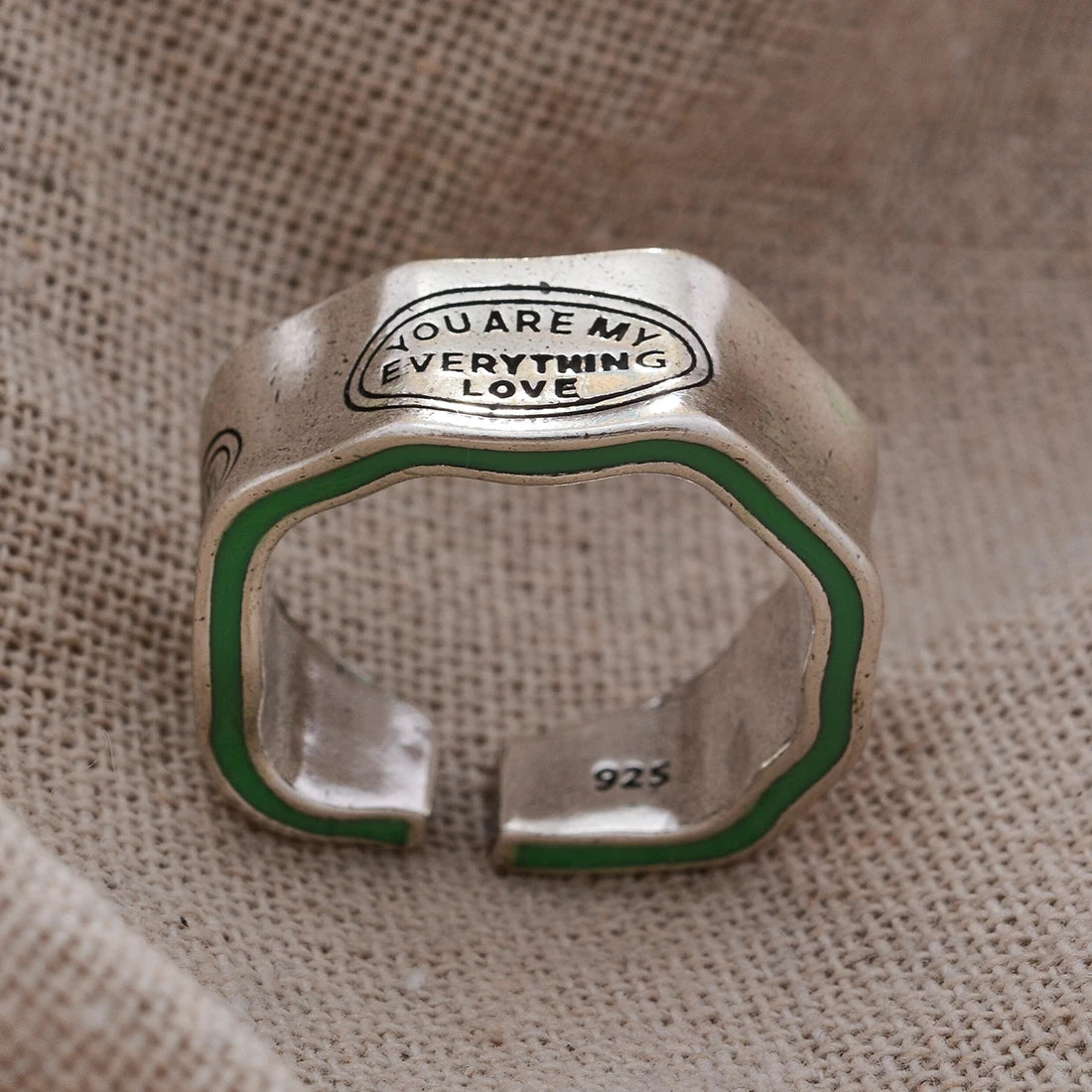 Silver ring with 'You are my everything love' engraving on a textured fabric background