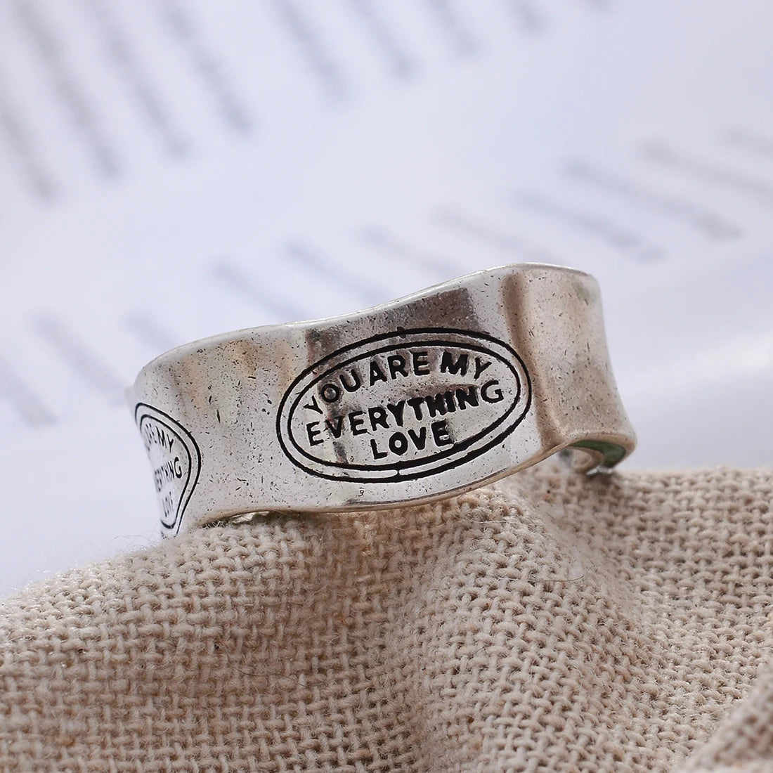 Silver ring with engraved text on a textured fabric background
