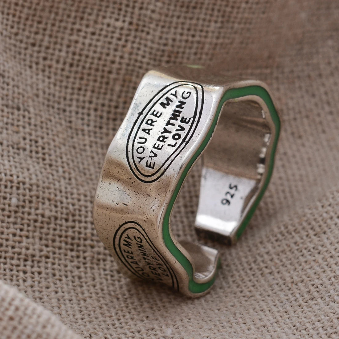 Silver ring with engraved text on a textured fabric background