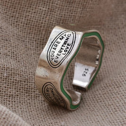 Silver ring with engraved text on a textured fabric background